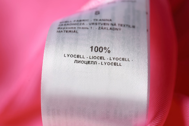 Clothing label with material content on pink shirt, closeup view