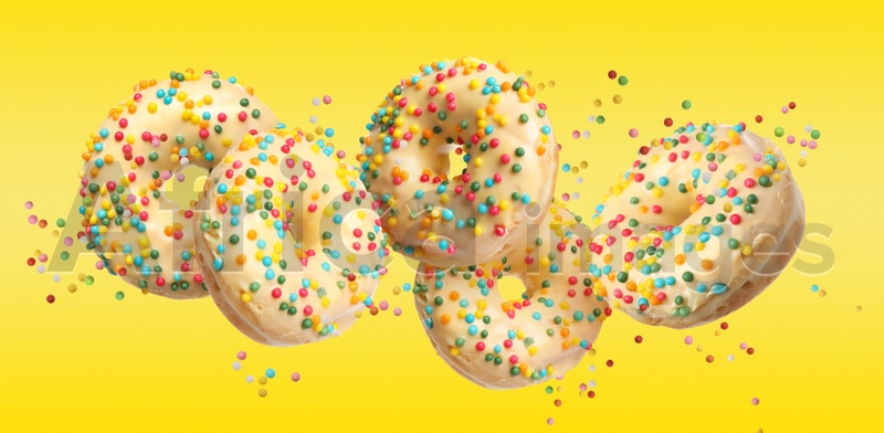 Image of Set of falling delicious donuts on yellow background. Banner design