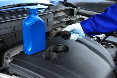 Photo of Worker checking motor oil level in car, closeup