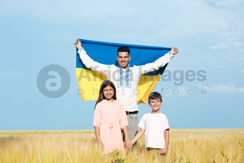 Happy family with national flag of Ukraine in field