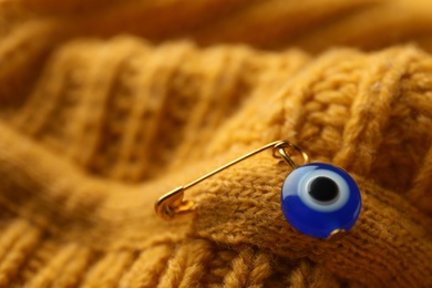 Evil eye safety pin on knitted clothing, closeup