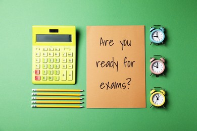 Flat lay composition with question Are you ready for exams, alarm clocks , calculator and pencils on green background