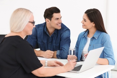 Young couple discussing pension plan with mature consultant in office