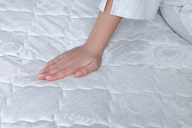 Photo of Woman touching soft white mattress, closeup view