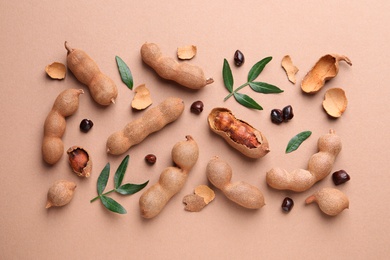 Ripe tamarinds and fresh leaves on beige background, flat lay
