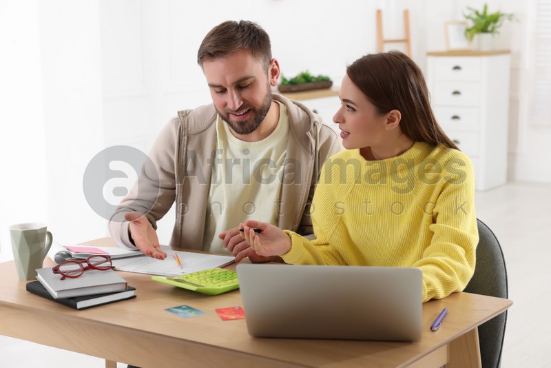 Young couple discussing family budget at table in living room