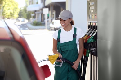 Young worker refueling car at modern gas station