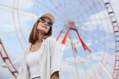 Beautiful young woman near Ferris wheel outdoors