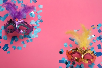Beautiful carnival masks and shiny confetti on pink background, flat lay. Space for text