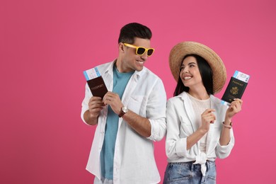 Couple of tourists with tickets and passports on pink background