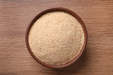 Fresh bread crumbs in bowl on wooden table, top view