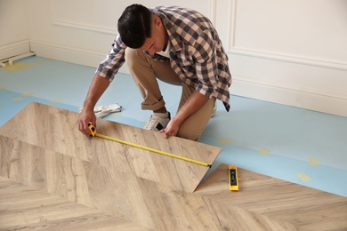 Professional worker installing new parquet flooring indoors