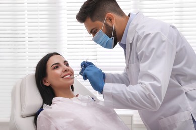 Dentist examining young woman's teeth in modern clinic