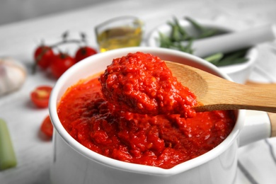 Spoon and pan with delicious tomato sauce, closeup view