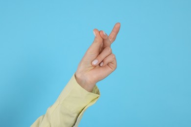 Woman snapping fingers on light blue background, closeup of hand