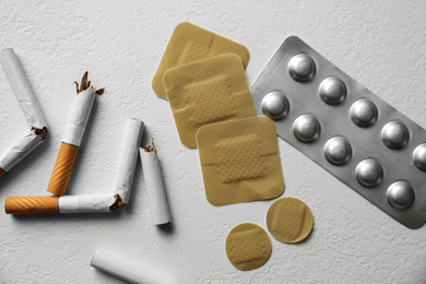 Nicotine patches, pills and broken cigarettes on white background, flat lay