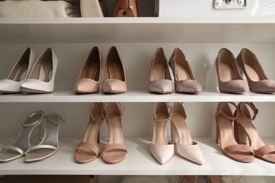 Photo of Different stylish women's shoes on shelving unit