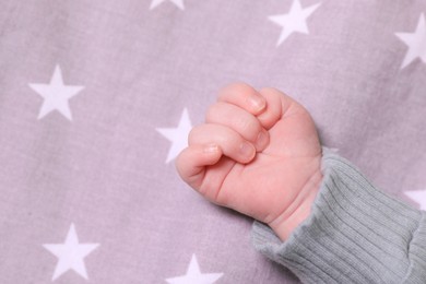 Cute newborn baby lying on bed, closeup of hand. Space for text