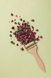 Photo of Creative flat lay composition with paint brush and dried rose buds on light green background