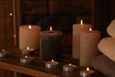 Photo of Spa composition with burning candles and towels on wooden table in wellness center