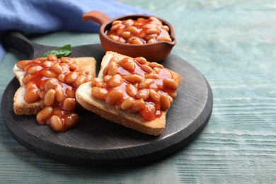 Toasts with delicious canned beans on light blue wooden table
