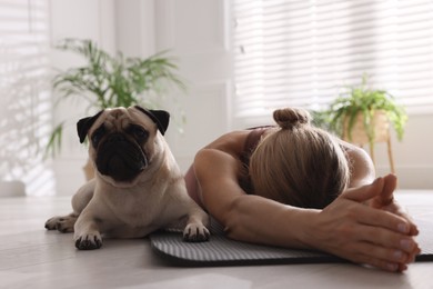 Woman with dog practicing yoga at home