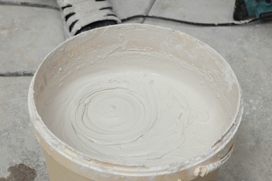Bucket with plaster on concrete floor indoors, closeup