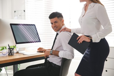 Young woman flirting with her colleague during work in office