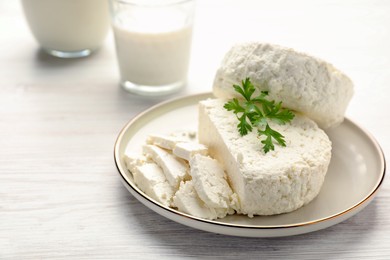 Delicious fresh cottage cheese with parsley on white wooden table