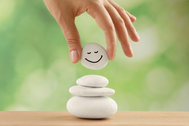 Woman putting stone with drawn happy face on stack, closeup Zen concept