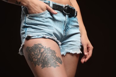 Woman with tattoos on body against black background, closeup