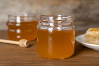 Glass jar with sweet honey on table, closeup