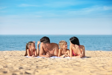 Happy family on sandy beach near sea. Summer holidays