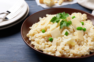 Delicious risotto with cheese on blue wooden table, closeup