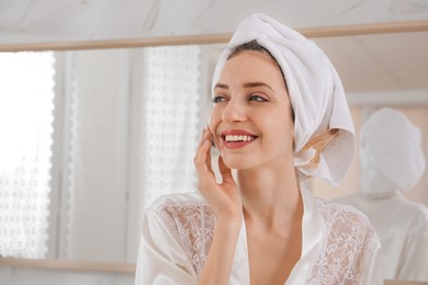 Beautiful young woman with hair wrapped in towel after washing at home