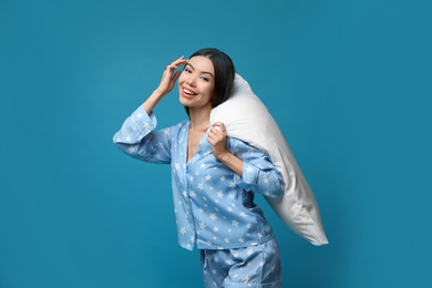 Beautiful Asian woman with pillow on blue background. Bedtime
