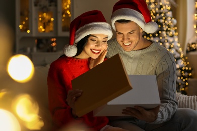 Happy couple opening magic gift box at home. Christmas celebration
