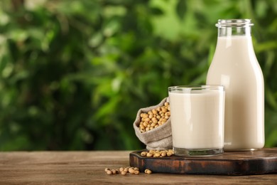 Fresh soy milk and grains on white wooden table against blurred background. Space for text
