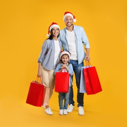Happy family with paper bags on yellow background. Christmas shopping