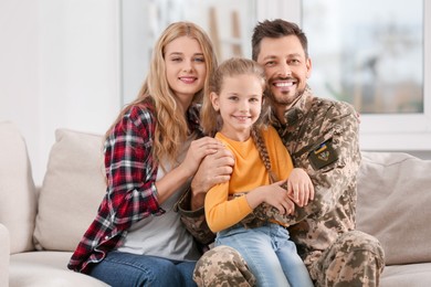 Soldier in Ukrainian military uniform reunited with his family on sofa at home