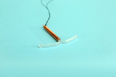 T-shaped intrauterine birth control device on turquoise background