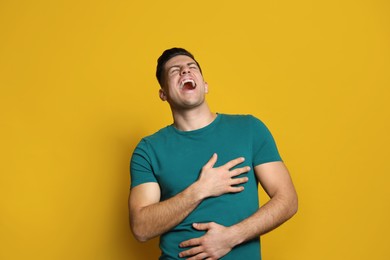 Handsome man laughing on yellow background. Funny joke