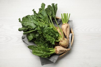 Photo of Basket with fresh sugar beets on white wooden table, top view