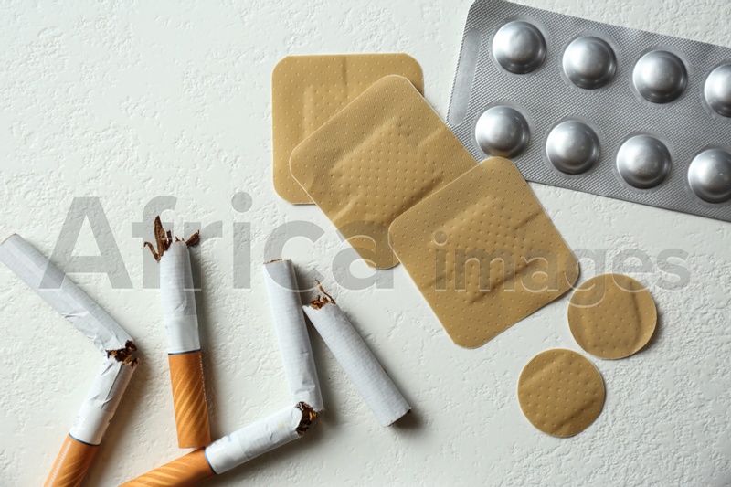 Nicotine patches, pills and broken cigarettes on white background, flat lay