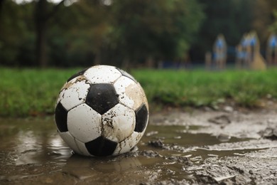 Photo of Dirty leather soccer ball in puddle outdoors