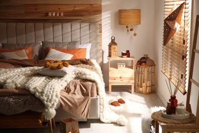 Cozy bedroom interior with knitted blanket and cushions