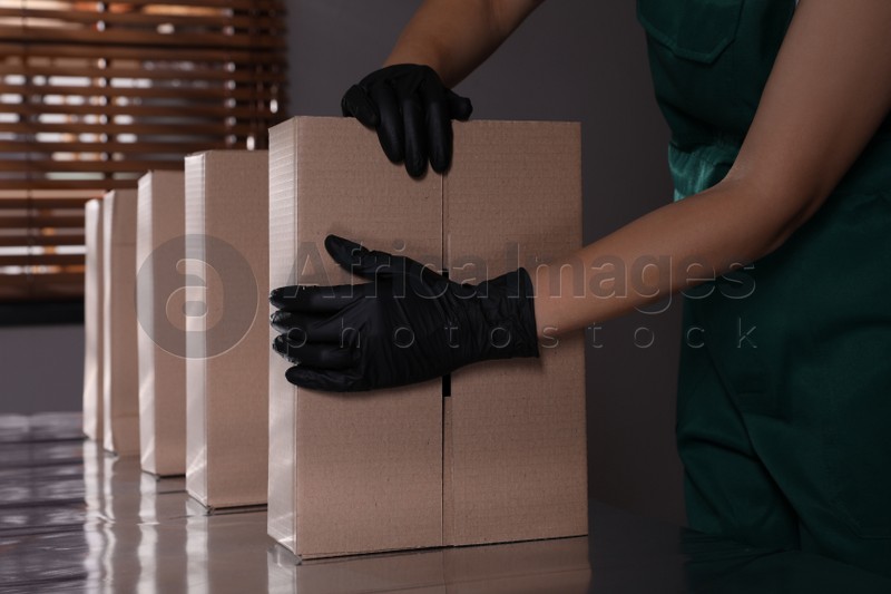 Woman packing cardboard boxes at production line indoors, closeup