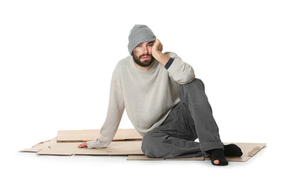 Poor homeless man sitting on cardboard, white background