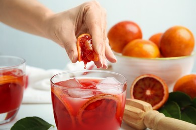 Woman squeezing sicilian orange juice into glass, closeup