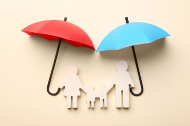 Mini umbrellas and family figure on beige background, flat lay
